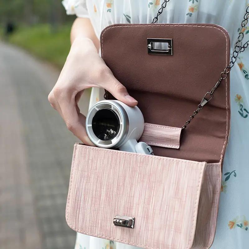 Compact silver foldable fan, folded for travel, USB-C rechargeable.
