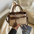 Crossbody tote bag with tan canvas body and brown leather trim, two top handles and detachable strap