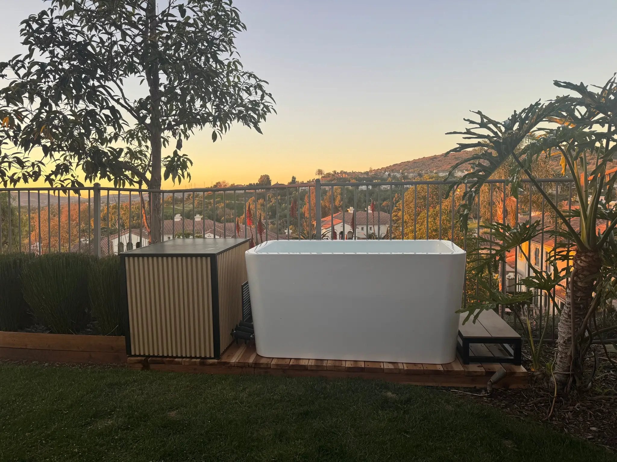 RevX Wellness acrylic X tub cold plunge with LUX High-Performance chiller on a wooden deck at sunset.