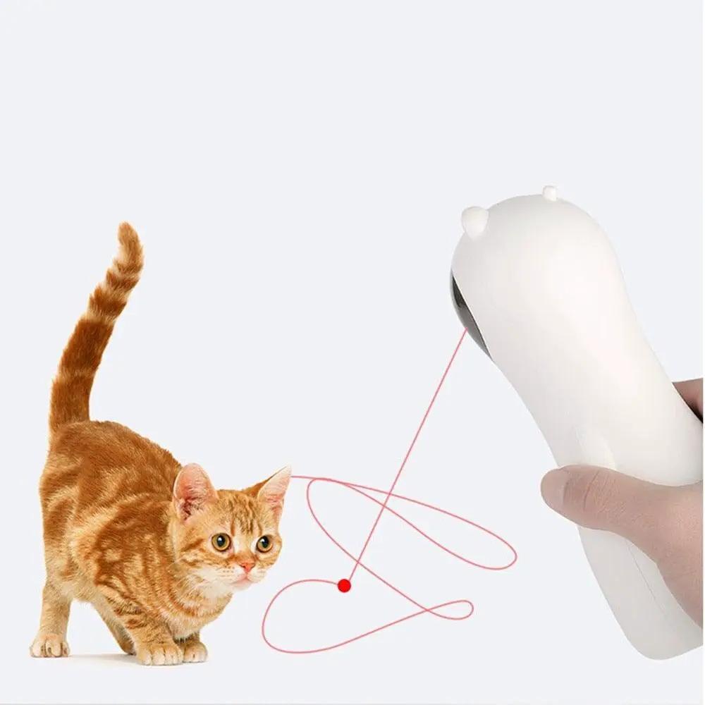 Stevvex handheld automatic cat teaser laser toy in white, emitting a red laser for indoor interactive play with an orange tabby