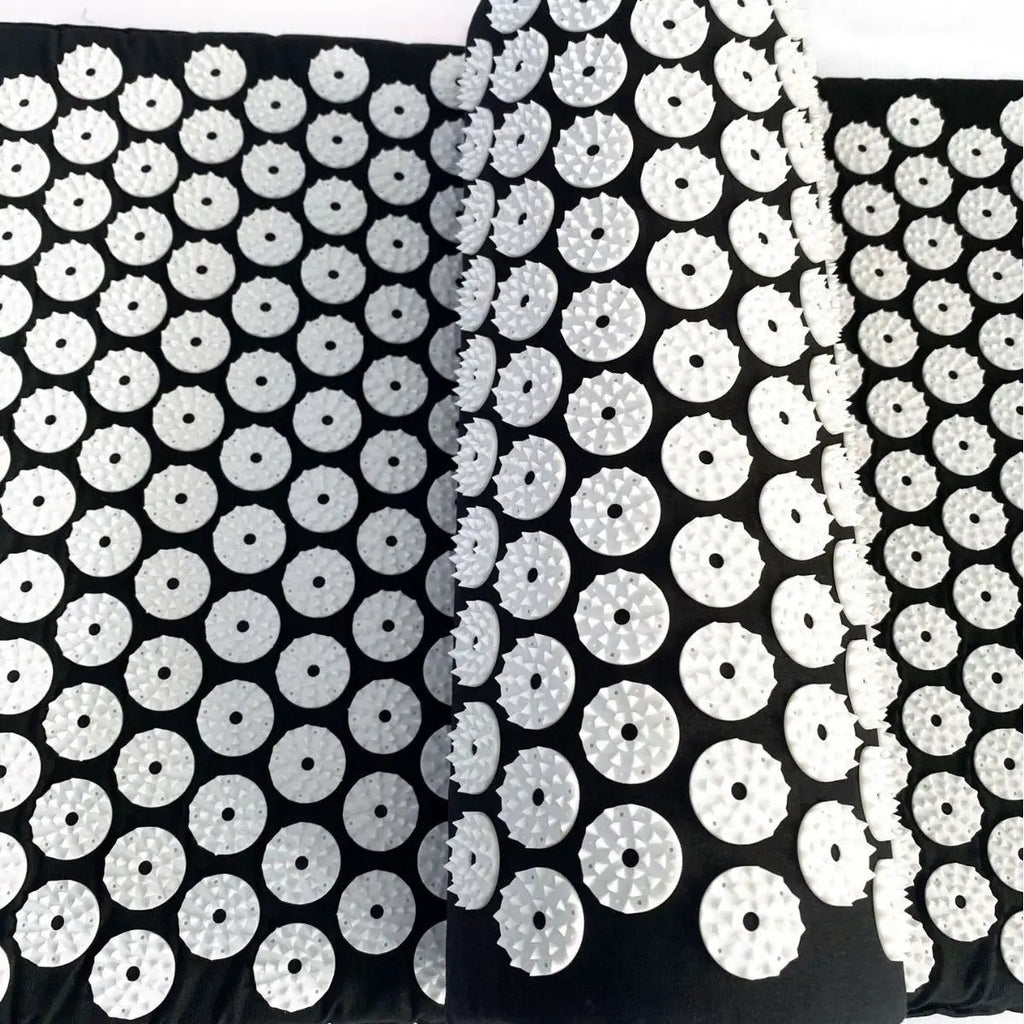Drip Sweat Lotus Wellness acupressure mat with pillow; black mat covered in white circular discs