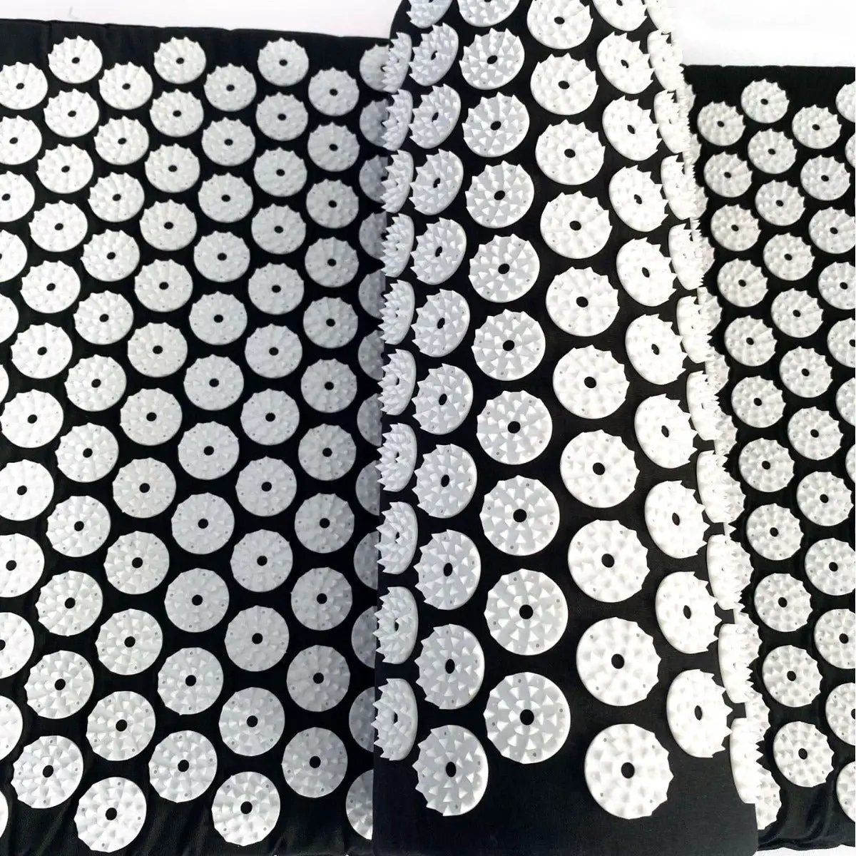 Drip Sweat Lotus Wellness acupressure mat with pillow; black mat covered in white circular discs