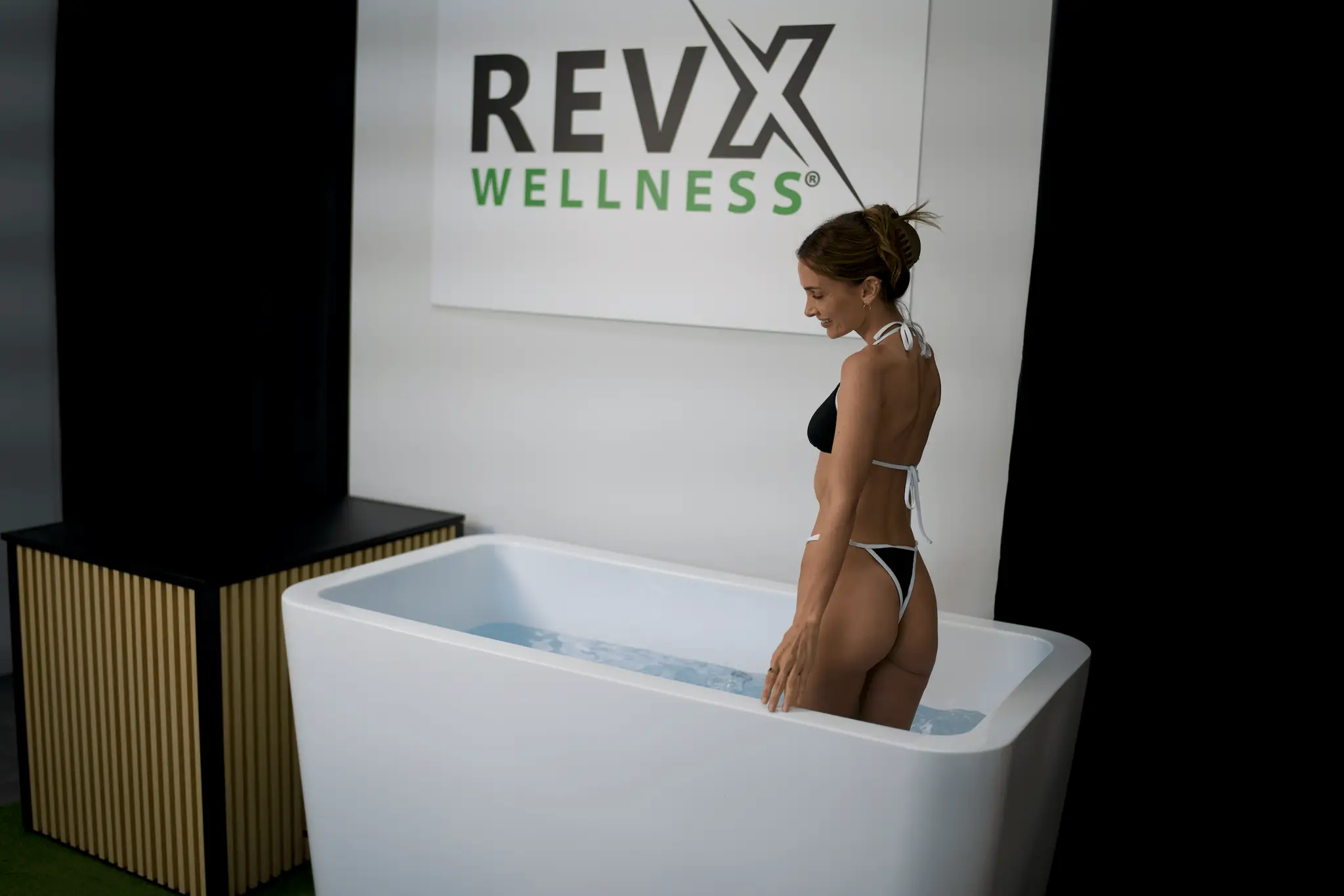 RevX Acrylic X Tub Cold Plunge with LUX High Performance Chiller, woman in white bikini beside white tub.
